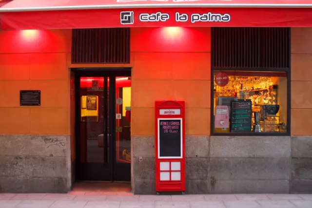 A red frontage with a lit sign, a red chalkboard and a display window