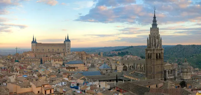 A hilltop town in morning light, with a square fortress and towers at one end and a cathedral spire at the other
