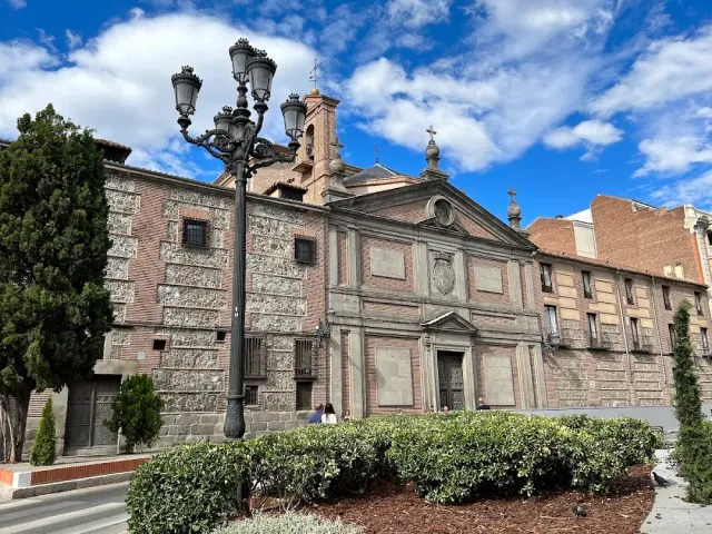 A stone and brick facade with a bell tower and a cross, and a tall black street lamp in front