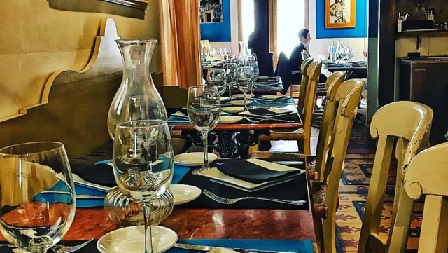 Set tables with glass carafes and pale wooden chairs, and pictures on blue walls