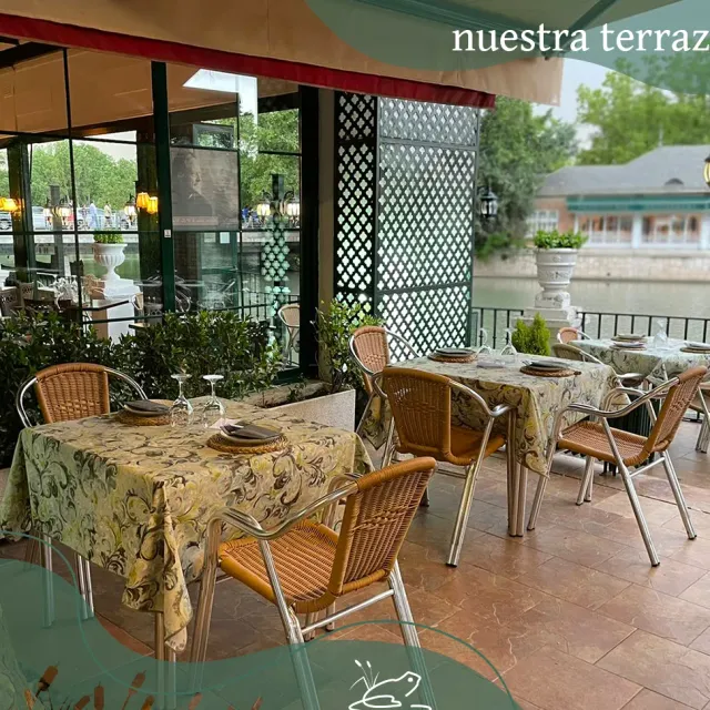 A covered terrace with wicker chairs and floral tablecloths, and a green lattice and garden behind