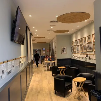 A café corridor with black leather armchairs and framed old photographs on the wall