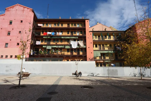 A pink residential building with open balcony galleries on every floor and washing hung out