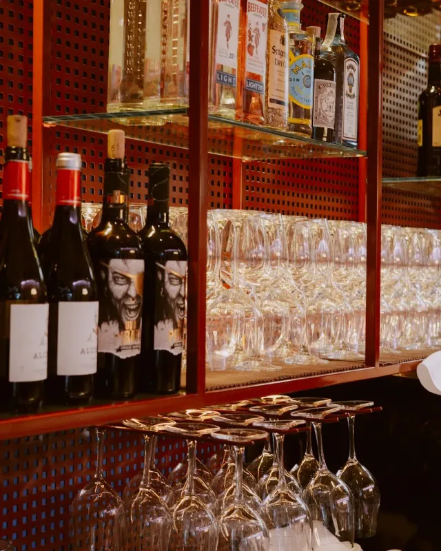 Bar shelves with wine and liquor bottles and rows of arranged glasses