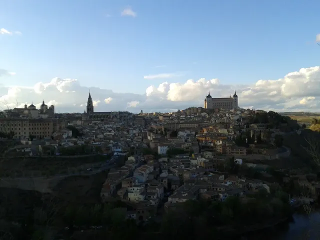 A view from an opposite hill of a dense old town on a hill, with a fortress and cathedral at its top