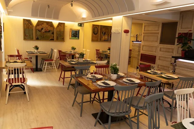 A bright dining room with a vaulted ceiling, set tables and colorful wooden chairs