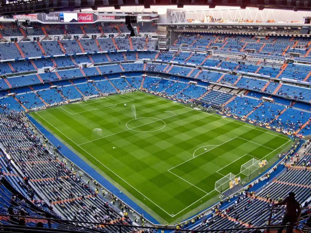 A green football pitch ringed by steep three tier stands, seen from high up