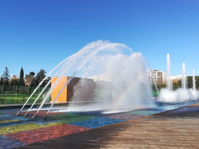Large jets of water in a fountain with a rainbow in the spray, and a wooden deck in front