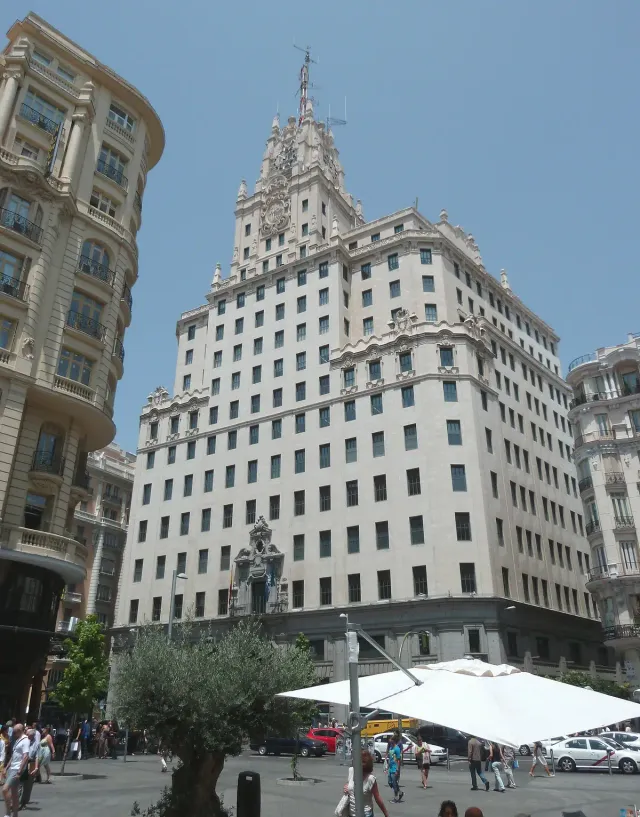A stepped white 1920s skyscraper with a central tower against a blue sky