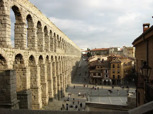 A two tier Roman stone aqueduct rising above a paved town square