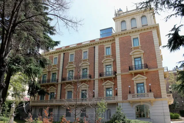 A nineteenth century town palace with an ornate facade and balconies, surrounded by a garden