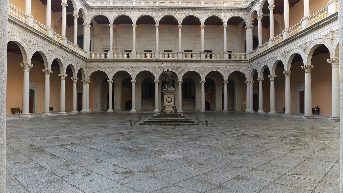 A square inner courtyard with two tiers of stone arcades and a bronze statue on a plinth at its centre