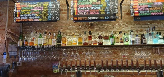 A row of beer taps under chalkboards listing beers on a brick wall
