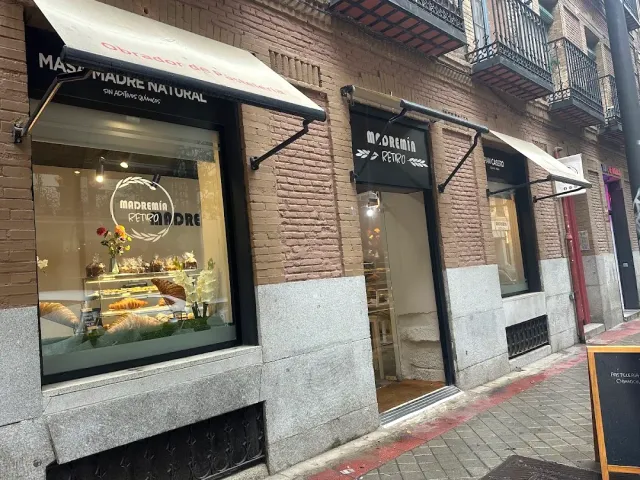 A street frontage with white awnings and a display window holding pastries on trays