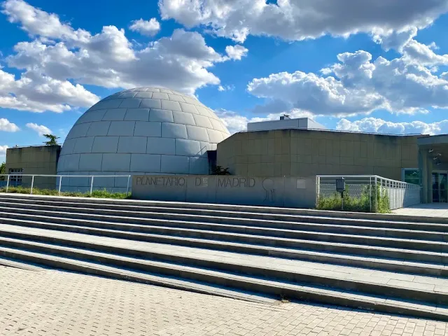 A building with a round metal dome and wide steps in front under a cloudy sky