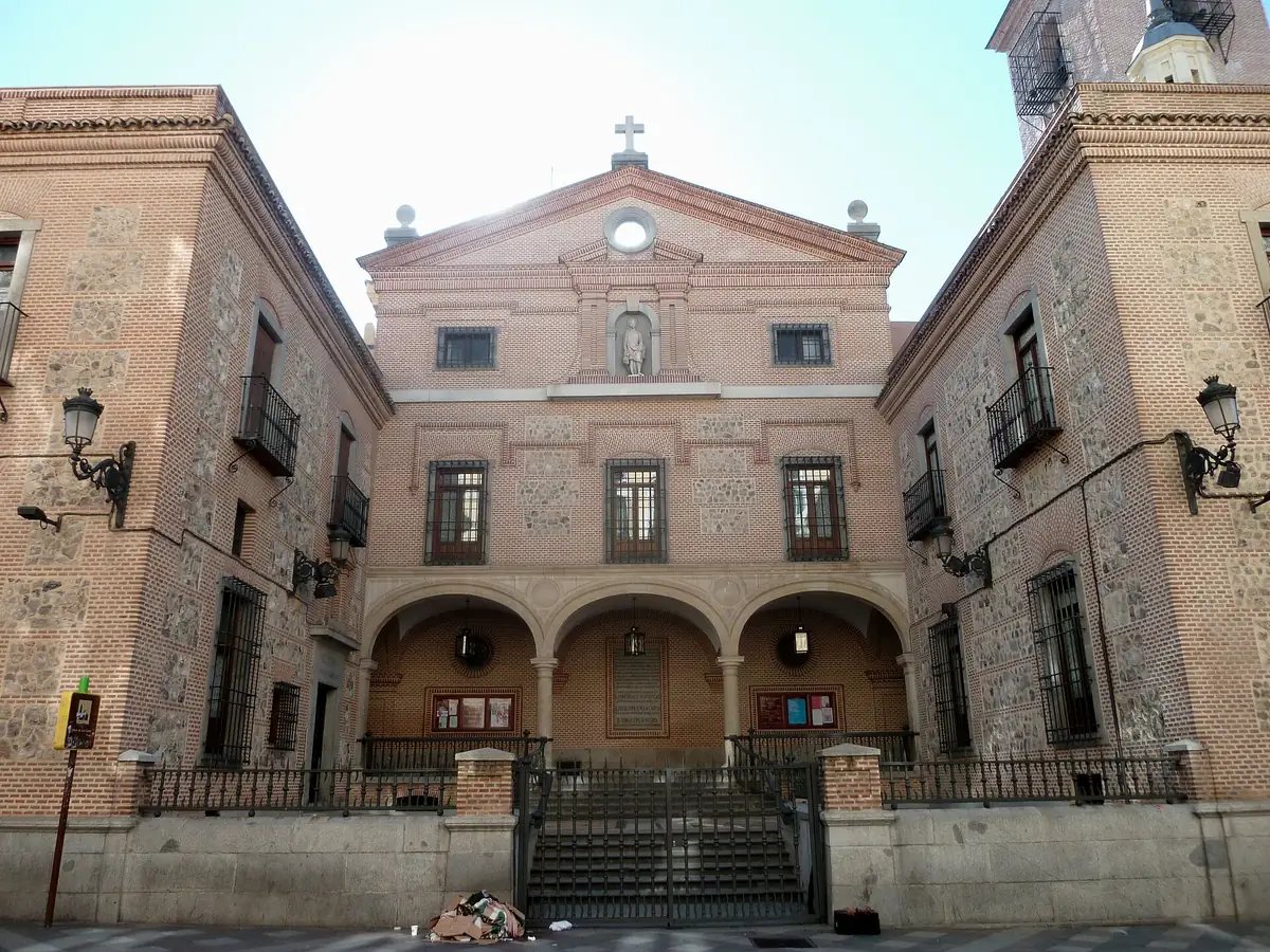 A brick and stone church front with three covered arches, a pediment and a statue in a niche above them