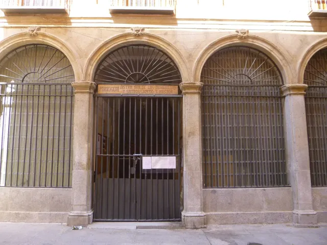 A stone church front with three deep arches behind iron gates