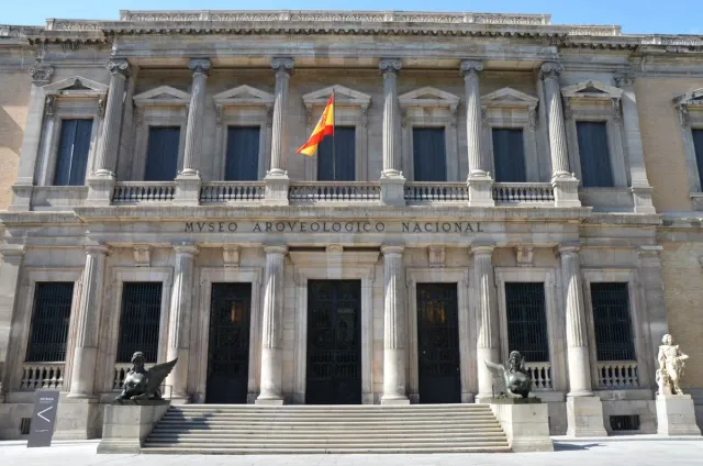 A neoclassical facade with tall columns and broad steps, with a flag flying above