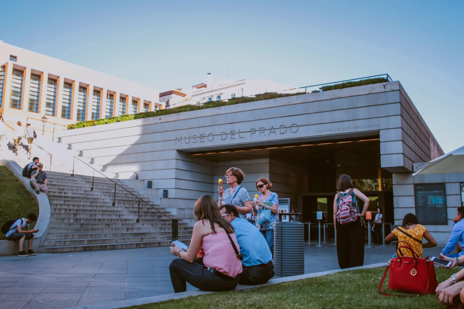 Visitors sitting on the steps outside the modern entrance to the Prado Museum in Madrid, Spain
