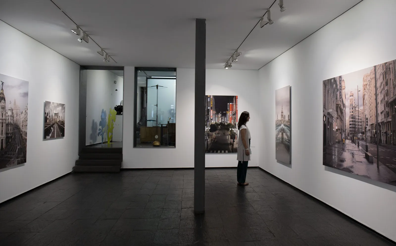 A visitor looking at large modern paintings in a bright gallery room of the Reina Sofía museum in Madrid, Spain