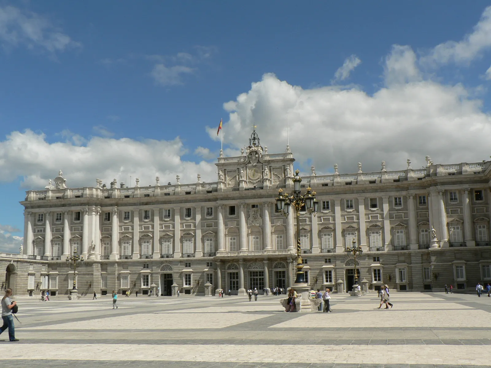 The Royal Palace of Madrid, its vast white baroque facade above the Plaza de Oriente in daylight
