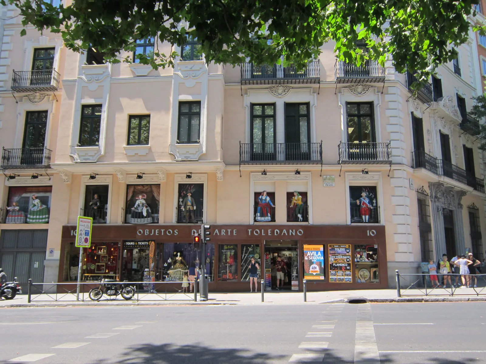 a wide tree lined shopping street in Madrid Spain with elegant shopfronts and pedestrians in daylight