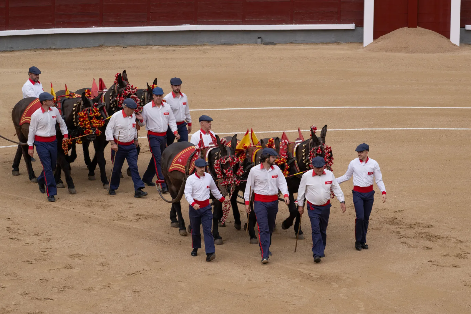 Men in white shirts leading horses at a bullring in Madrid, Spain
