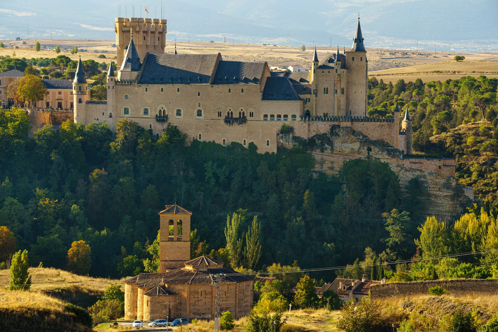 The Alcazar of Segovia on its rocky spur above wooded slopes in Spain